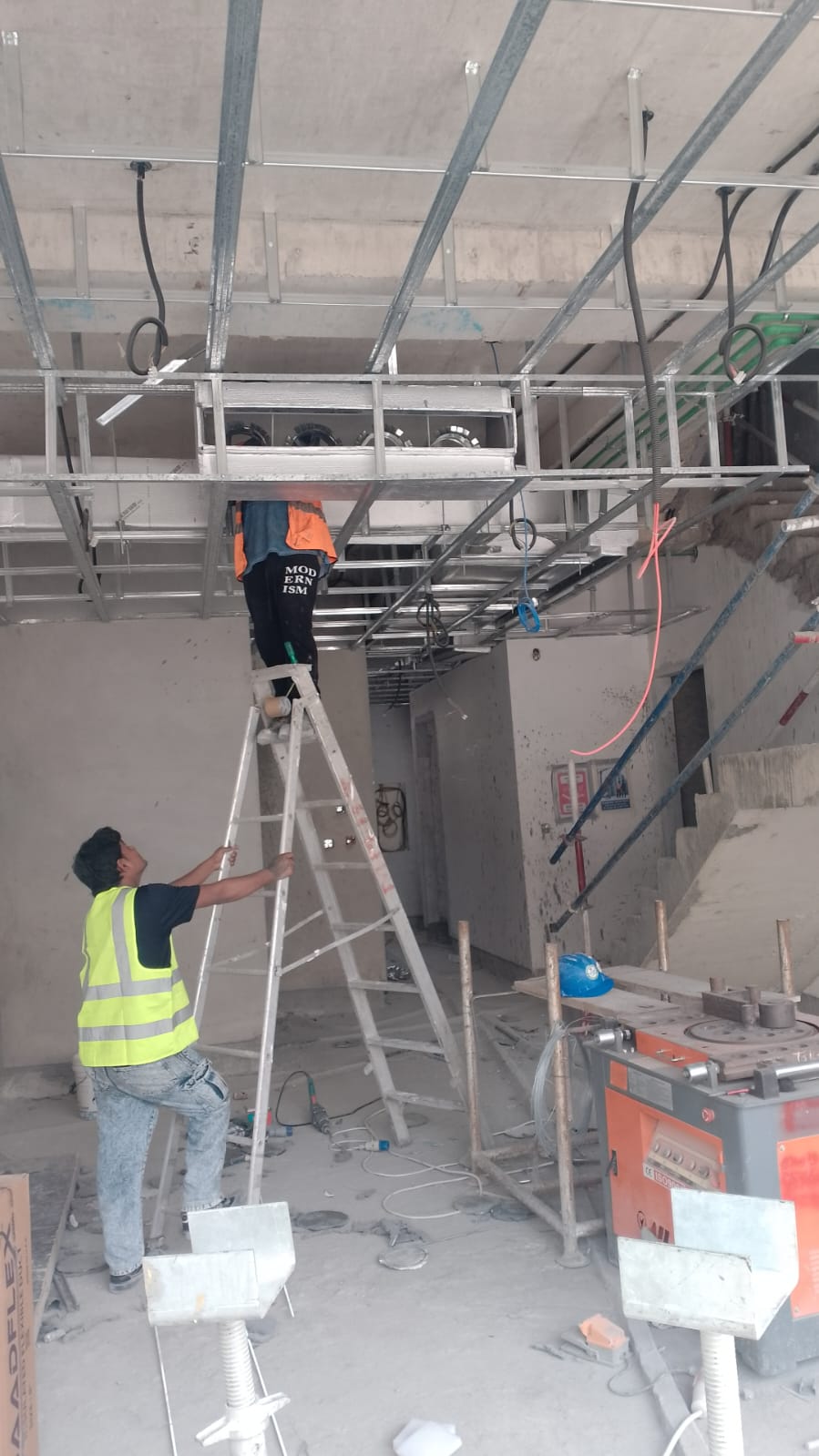 يقوم فني التركيب في الموقع بمحاذاة مجاري الهواء وخدمات التدفئة والتهوية وتكييف الهواء (HVAC) العلوية.