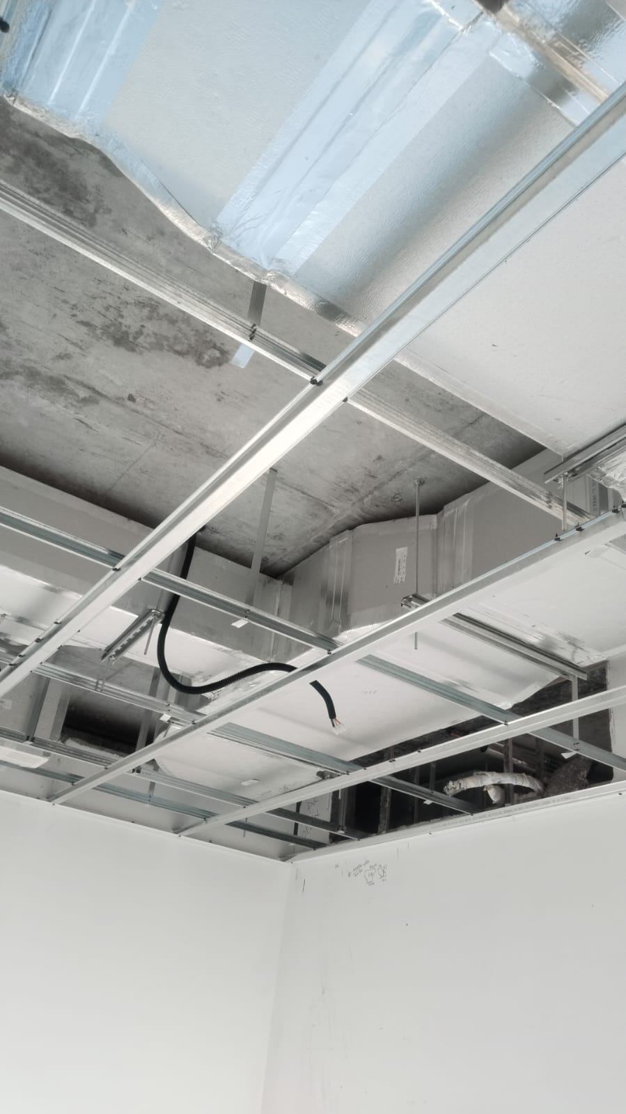 Insulated HVAC ductwork above suspended-ceiling metal framing during installation.